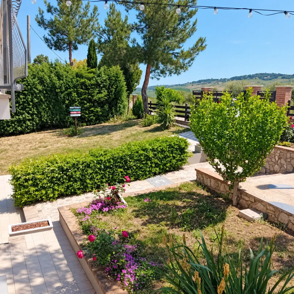 The fenced garden of Villa Nonno Nicola, with the lawn and the hills